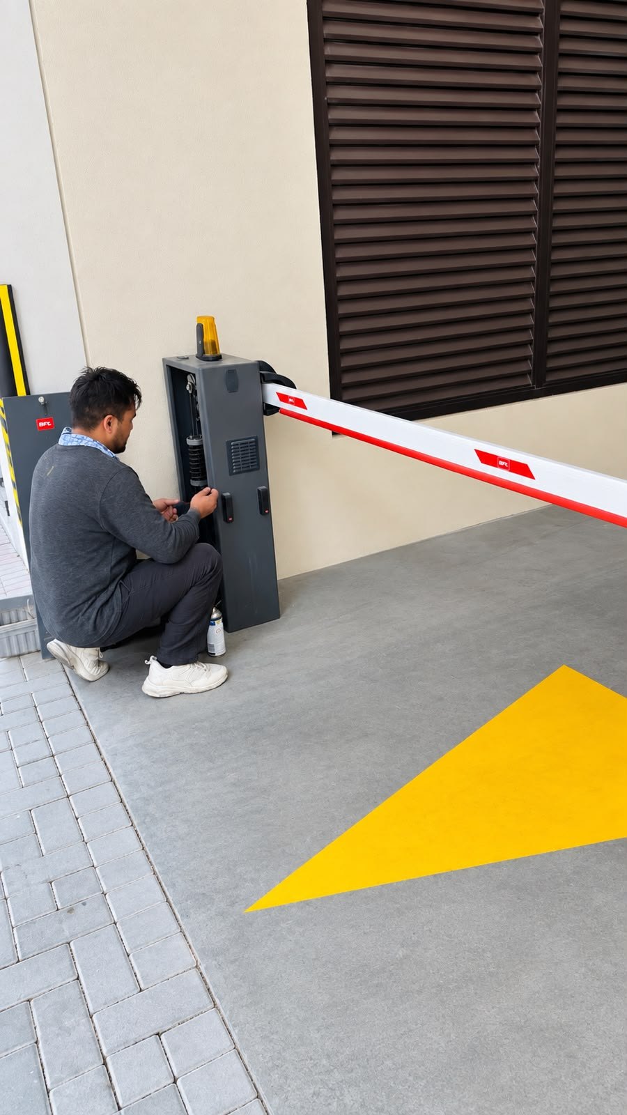 Technician servicing a BFT gate barrier cabinet at a car park entrance in Al Karama, Dubai