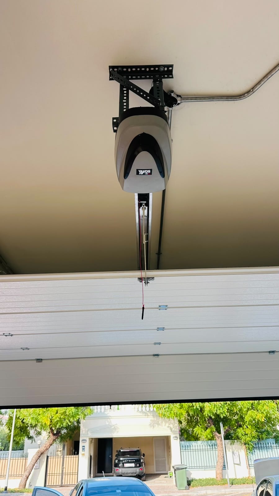VDS garage door operator with rail and release cord mounted on the ceiling above a sectional door in Mudon, Dubai