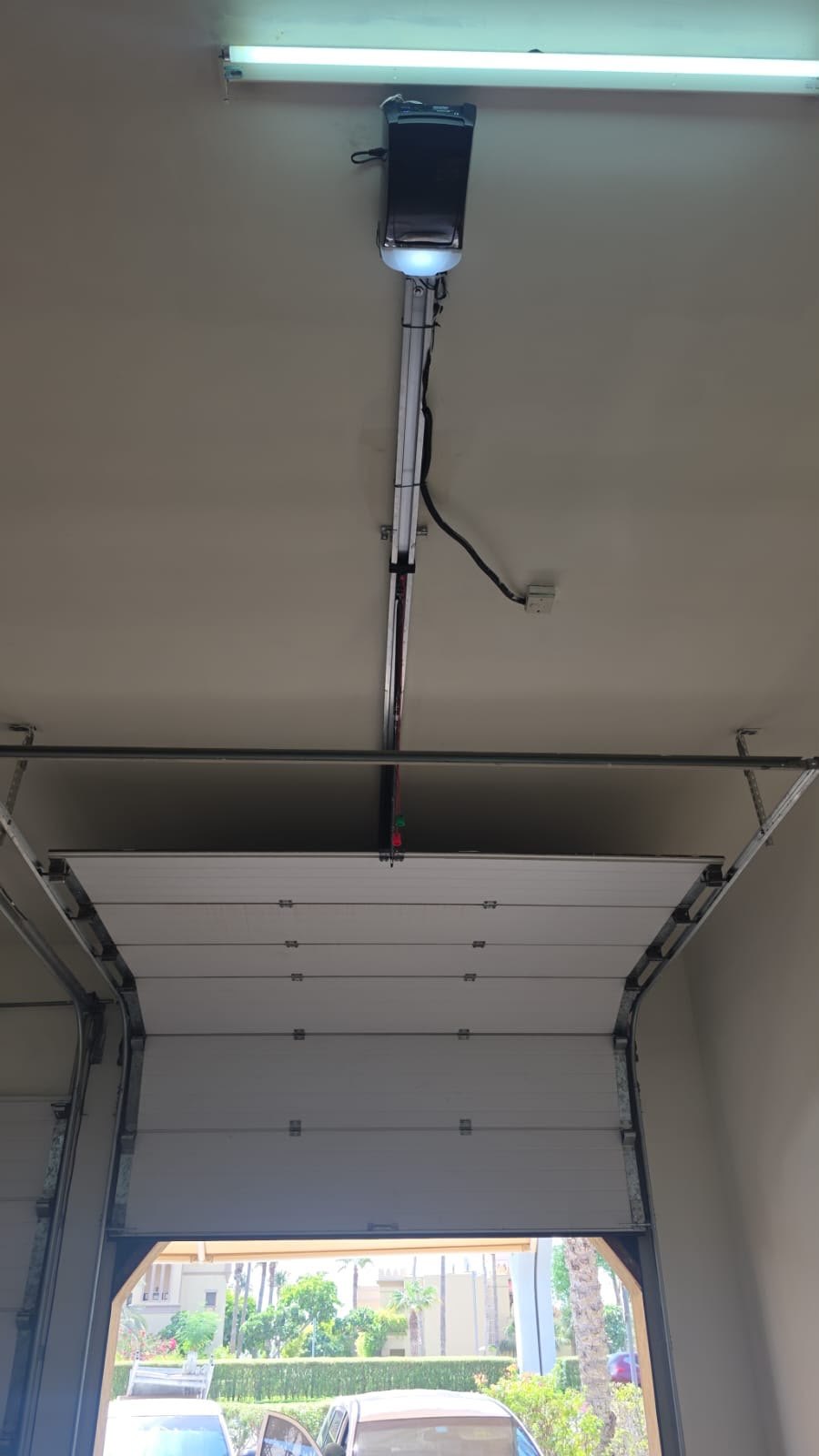 Ceiling-mounted garage door motor with rail and light on a sectional garage door in Palm Jumeirah, Dubai