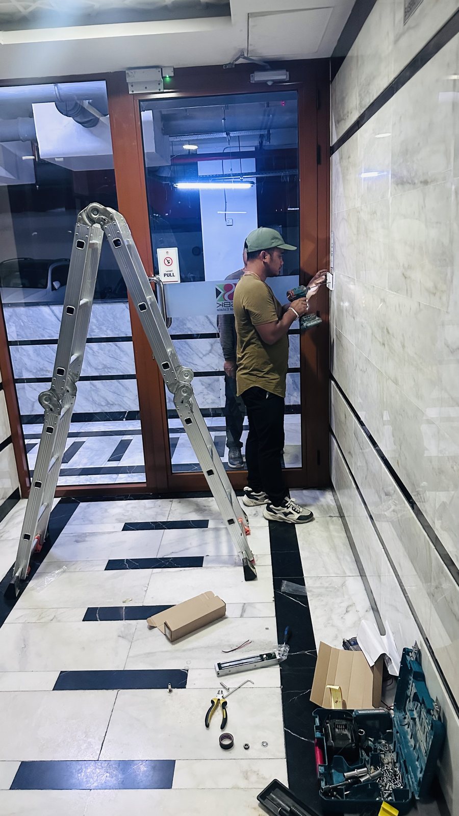 Technician on a ladder replacing a magnetic lock at an access controlled entrance in Al Jaddaf, Dubai