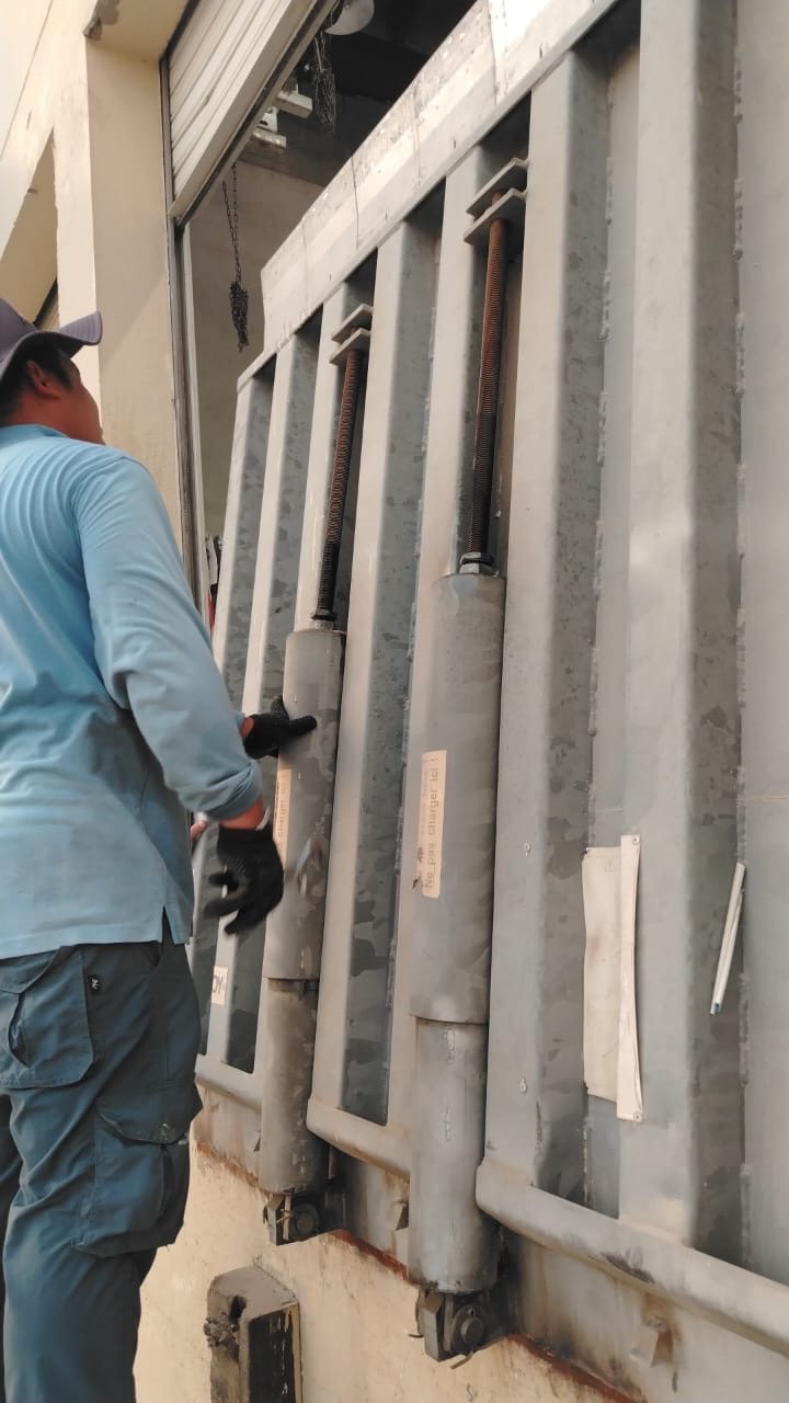Technician repairing the springs of a manual dock leveler at a loading bay in Dubai Industrial City