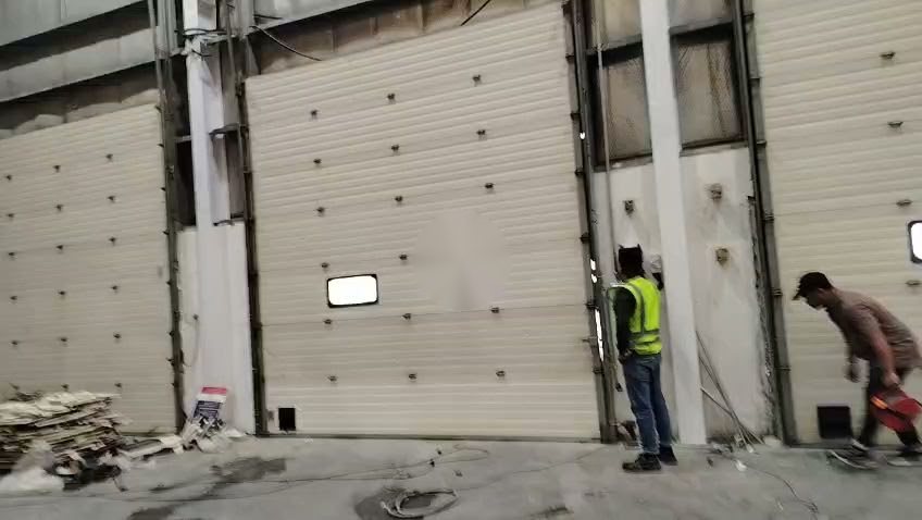 Technicians fitting a Marantec side motor operator to an existing sectional door in Jebel Ali Free Zone, Dubai