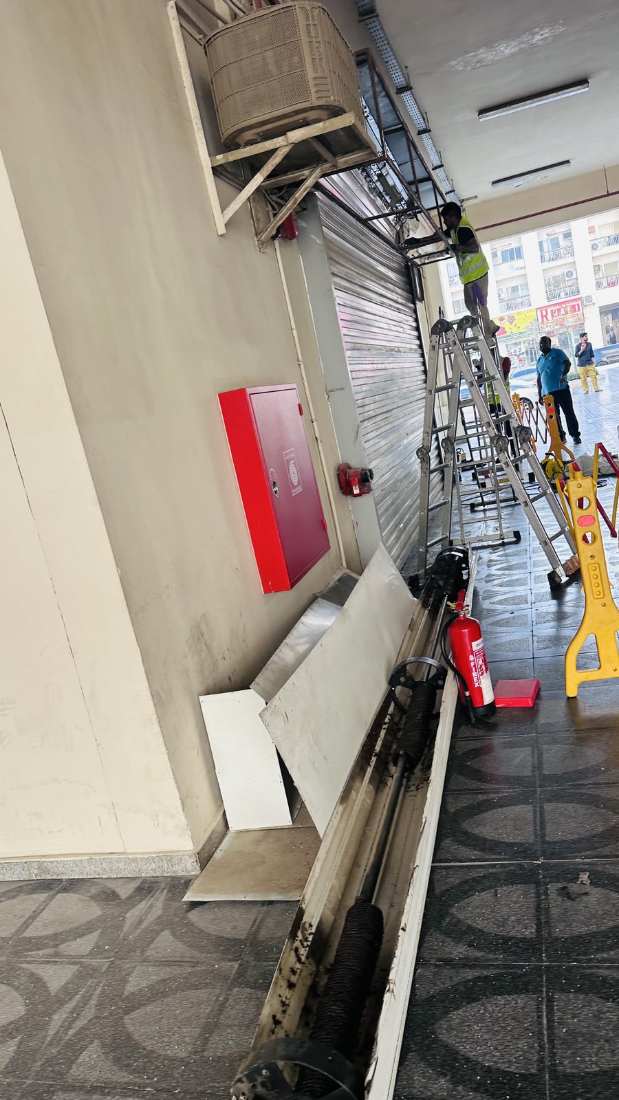 Technician on a ladder replacing the motor of a rolling shutter in Al Karama, Dubai