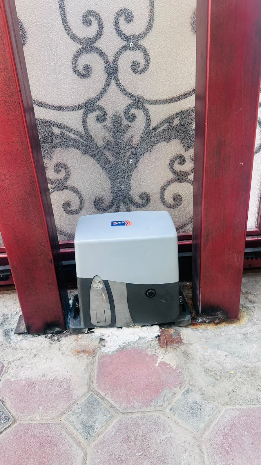Sliding gate motor installed at the foot of a red panel gate on Al Wasel Road, Dubai